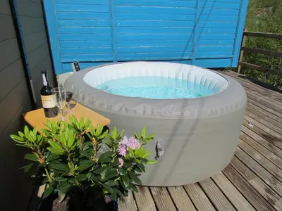a hot tub with a table and a bottle of wine at Cuckoo at Wild Valley Huts in Oswestry
