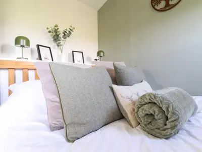 a pile of pillows on a bed in a bedroom at Cuckoo at Wild Valley Huts in Oswestry