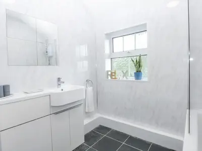 a white bathroom with a sink and a mirror at Tawelfan in Llwyngwril