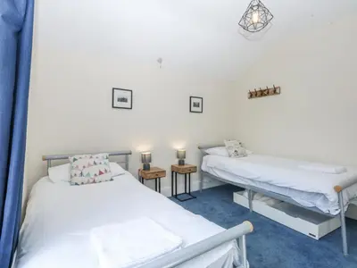 a room with two beds and two tables in it at Tawelfan in Llwyngwril