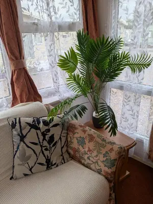 a living room with a chair and a plant in a window at The fox den in Rhos-gôch
