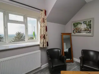 a living room with two chairs and a window at Mynydd ar Mor in Barmouth