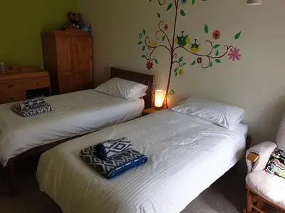 two beds in a room with a tree on the wall at Y Garth, Sleeps 12 in Barmouth