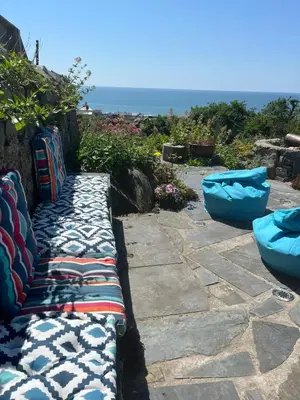 a bench with pillows sitting on top of a patio at Y Garth, Sleeps 12 in Barmouth