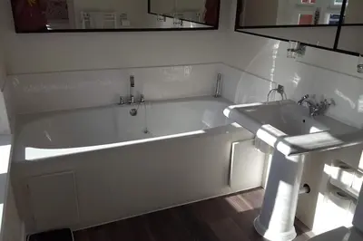 a bathroom with a bath tub and a sink at Y Garth, Sleeps 12 in Barmouth