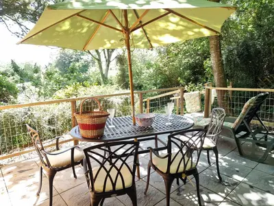 a table with chairs and an umbrella on a patio at Arwel Llangrannog in Llanllwchaiarn