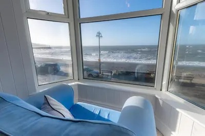a room with a blue chair and a view of the ocean at Plas Hafan Apartment 2 Aberystwyth in Aberystwyth