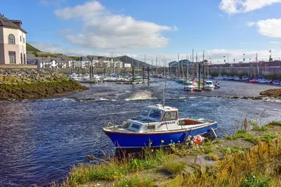 a boat sitting on the shore of a river with boats at Plas Hafan Apartment 2 Aberystwyth in Aberystwyth