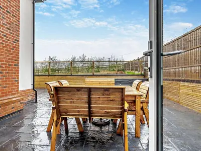 a patio with a wooden table and chairs on a balcony at 4 Bed in Bishops Castle 94072 in Bishops Castle