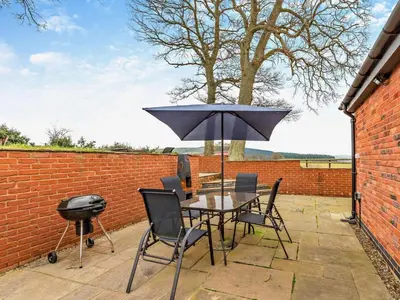 a patio with a table with an umbrella and a grill at 2 Bed in Craven Arms oc-94099 in Clun