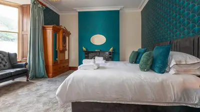 a bedroom with a large bed with a blue wall at The Belmont Barmouth in Barmouth