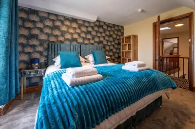 a bedroom with a large blue bed with towels on it at The Belmont Barmouth in Barmouth