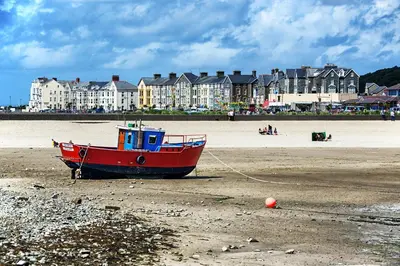 a red boat sitting on the sand on a beach at The Belmont Barmouth in Barmouth