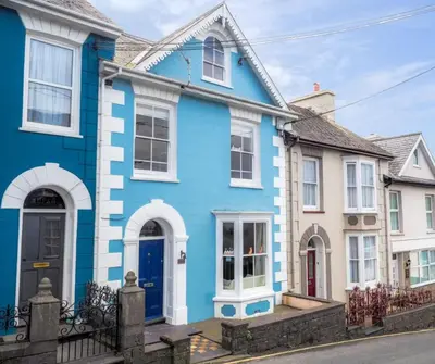 a blue house with white trim on a street at Brodawel New Quay in New Quay