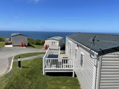 a small white house with a porch and the ocean at WH - Smugglers Cove 01 in Aberaeron