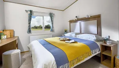 a bedroom with a large bed with a yellow and blue blanket at WH - Smugglers Cove 03 in Aberaeron