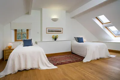 two beds in a room with white walls and windows at Bryn Isaf Tregaron in Ystrad-Meurig