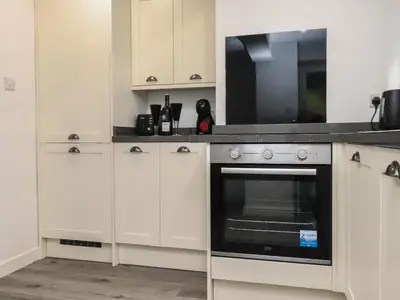 a kitchen with white cabinets and a black oven at Henllys in Harlech