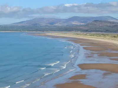 an aerial view of a beach with mountains in the background at Henllys in Harlech