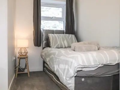 a small bedroom with a bed with a window at Henllys in Harlech