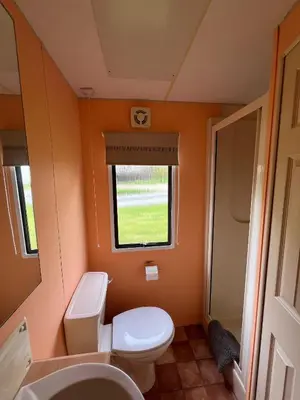 a small bathroom with a toilet and a sink at Spacious 2 bedroomed mobile home in Aberystwyth