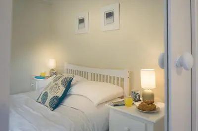 a bedroom with a white bed with two tables and two lamps at Ellesmere New Quay in New Quay
