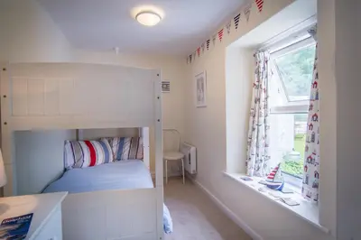 a small bedroom with a bunk bed and a window at Ellesmere New Quay in New Quay