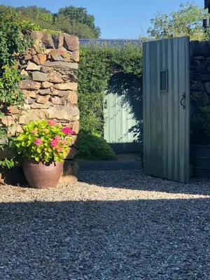 a stone wall with a gate and a pot of flowers at Cabin in the hills near Dolgellau in Dolgellau