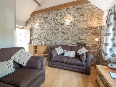 a living room with two couches and a stone wall at Briallen Aberystwyth in Llanrhystyd