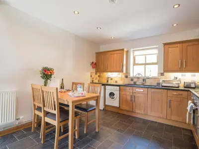 a kitchen with wooden cabinets and a wooden table and chairs at Briallen Aberystwyth in Llanrhystyd