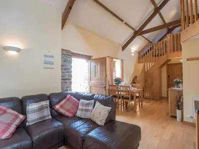 a living room with a leather couch and a table at Eirlys Aberystwyth in Llanrhystyd