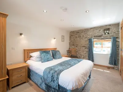 a bedroom with a large bed and a stone wall at Eirlys Aberystwyth in Llanrhystyd