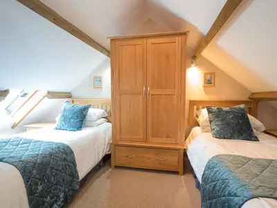 a attic bedroom with two beds and a cabinet at Eirlys Aberystwyth in Llanrhystyd