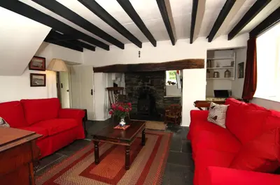 a living room with red couches and a fireplace at Cae Mawr Borth and Ynyslas in Scyborycoed