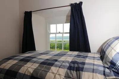 a bedroom with a bed and a window at Cae Mawr Borth and Ynyslas in Scyborycoed