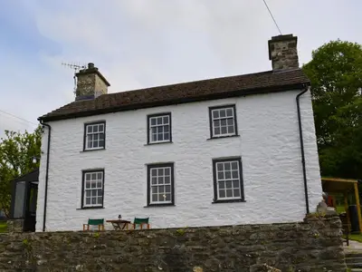 a white house with a table and chairs in front of it at Cae Mawr Borth and Ynyslas in Scyborycoed