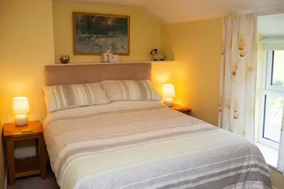 a bedroom with a bed with two lamps and a window at Soar Cottage Aberystwyth in Aberystwyth