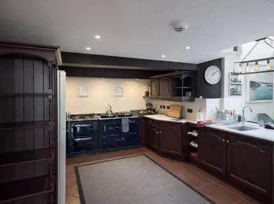 a kitchen with black cabinets and a clock on the wall at Glandwr hall - 6 Bed - Magnificent Country House with Heated Swimming Pool & Jacuzzi in Barmouth