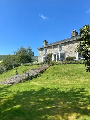 an old stone house on a grassy hill at Glandwr hall - 6 Bed - Magnificent Country House with Heated Swimming Pool & Jacuzzi in Barmouth