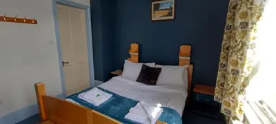 a small bedroom with a bed with blue walls at Kington Accommodation in Kington