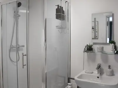 a white bathroom with a shower and a sink at Llety Cariad in Bala