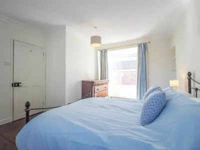 a bedroom with a blue bed with a window at Glenydd New Quay in New Quay