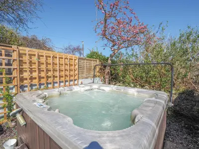 a hot tub in a backyard with a fence at Glenydd New Quay in New Quay