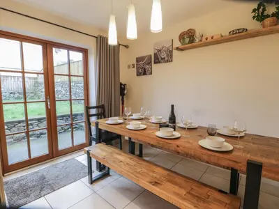 a dining room with a wooden table and a window at Anadlu in Llanbedr