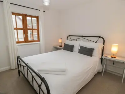 a bedroom with a large white bed with two lamps at Anadlu in Llanbedr