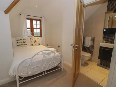 a bedroom with a bed and a bathroom with a toilet at Anadlu in Llanbedr