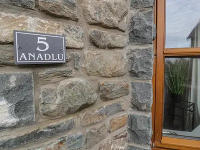 a sign on the side of a stone wall at Anadlu in Llanbedr