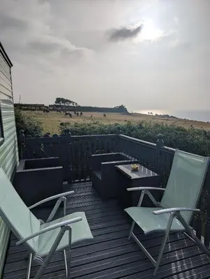 two chairs and a table on a deck with the ocean at 64 Wide Horizon in Aberaeron