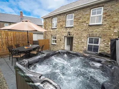 a hot tub on a patio in front of a house at Bryndalis Aberaeron in Ciliau-Aeron