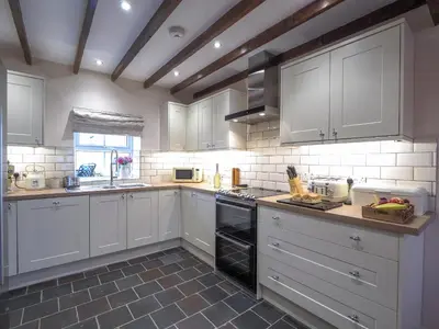 a kitchen with white cabinets and a black dishwasher at Bryndalis Aberaeron in Ciliau-Aeron
